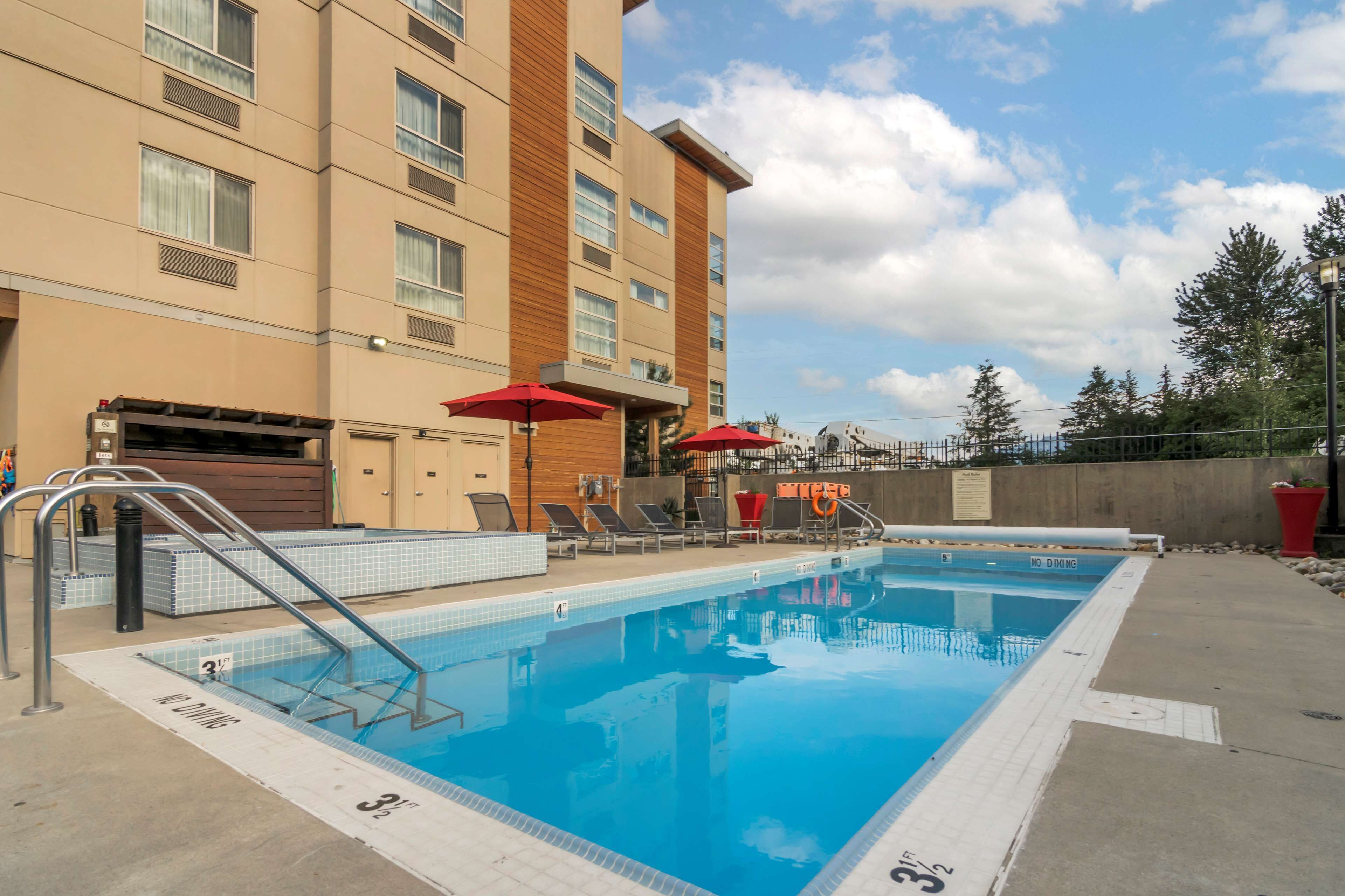 A swimming pool with a diving board, lounge chairs, and umbrellas.