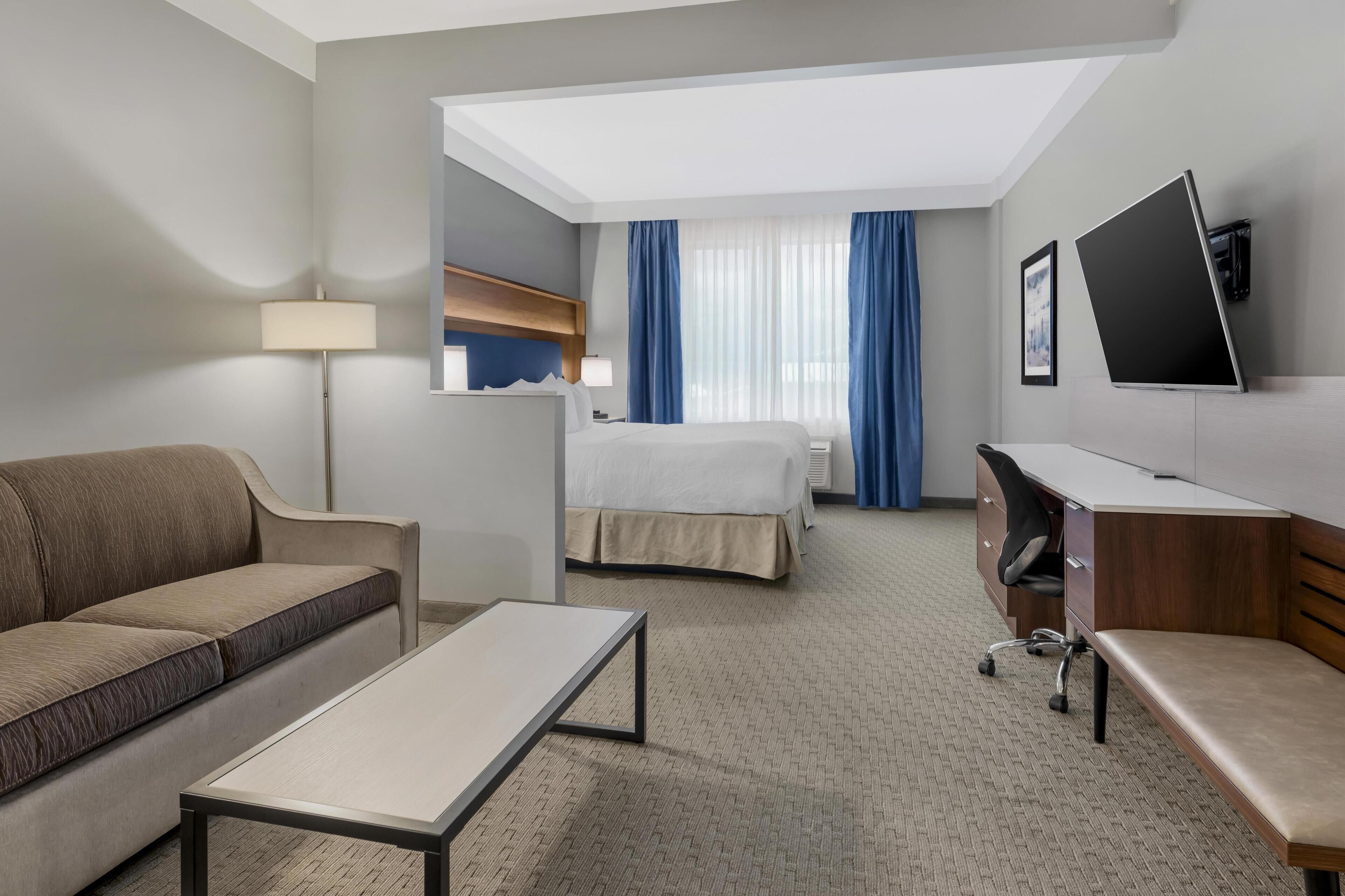 A hotel room with a sofa, a bed, a desk, and a TV.