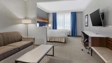 A hotel room with a sofa, a bed, a desk, and a TV.