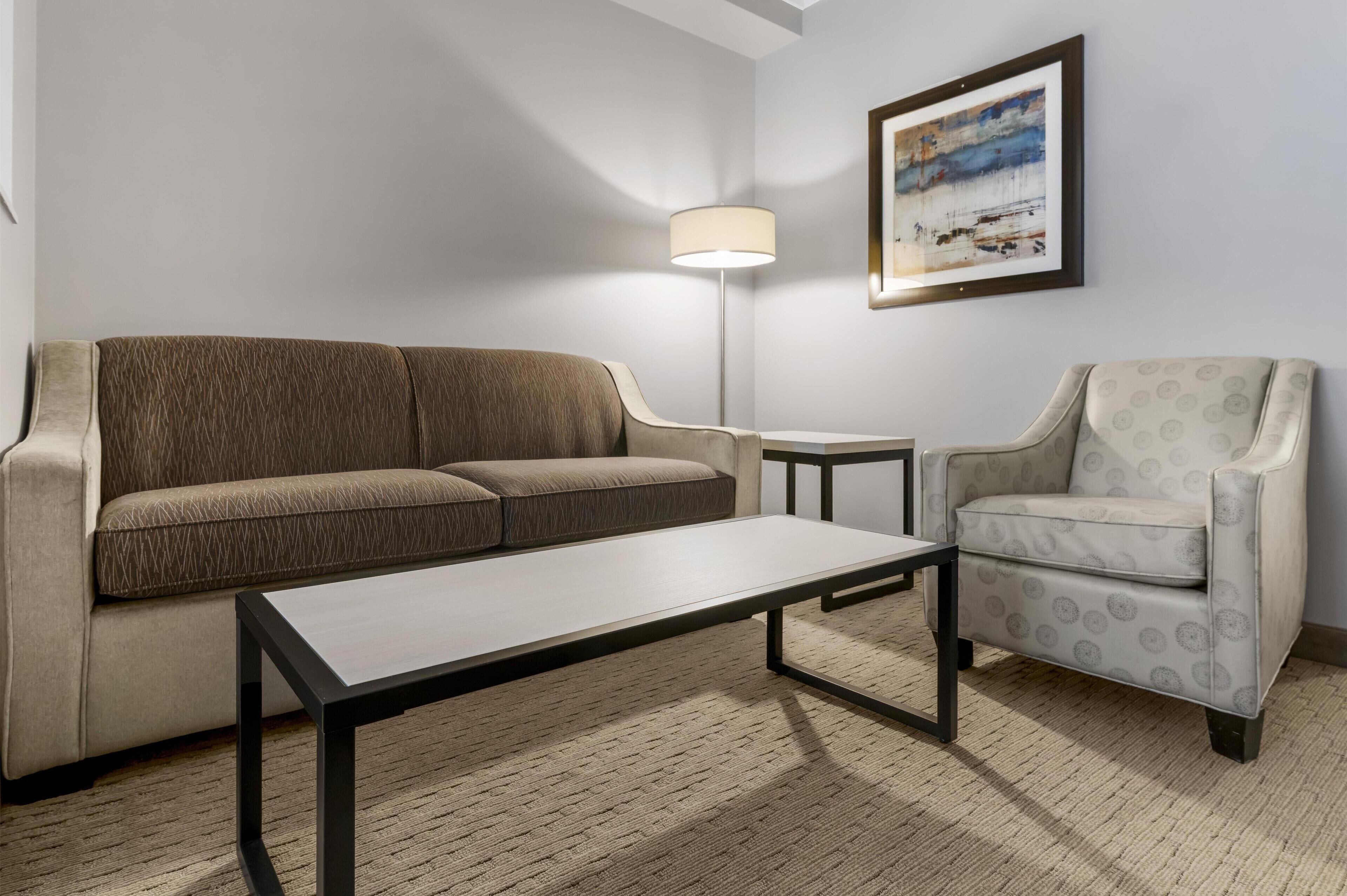 Un salon moderne comprenant un canapé, un fauteuil, une table basse et un lampadaire.