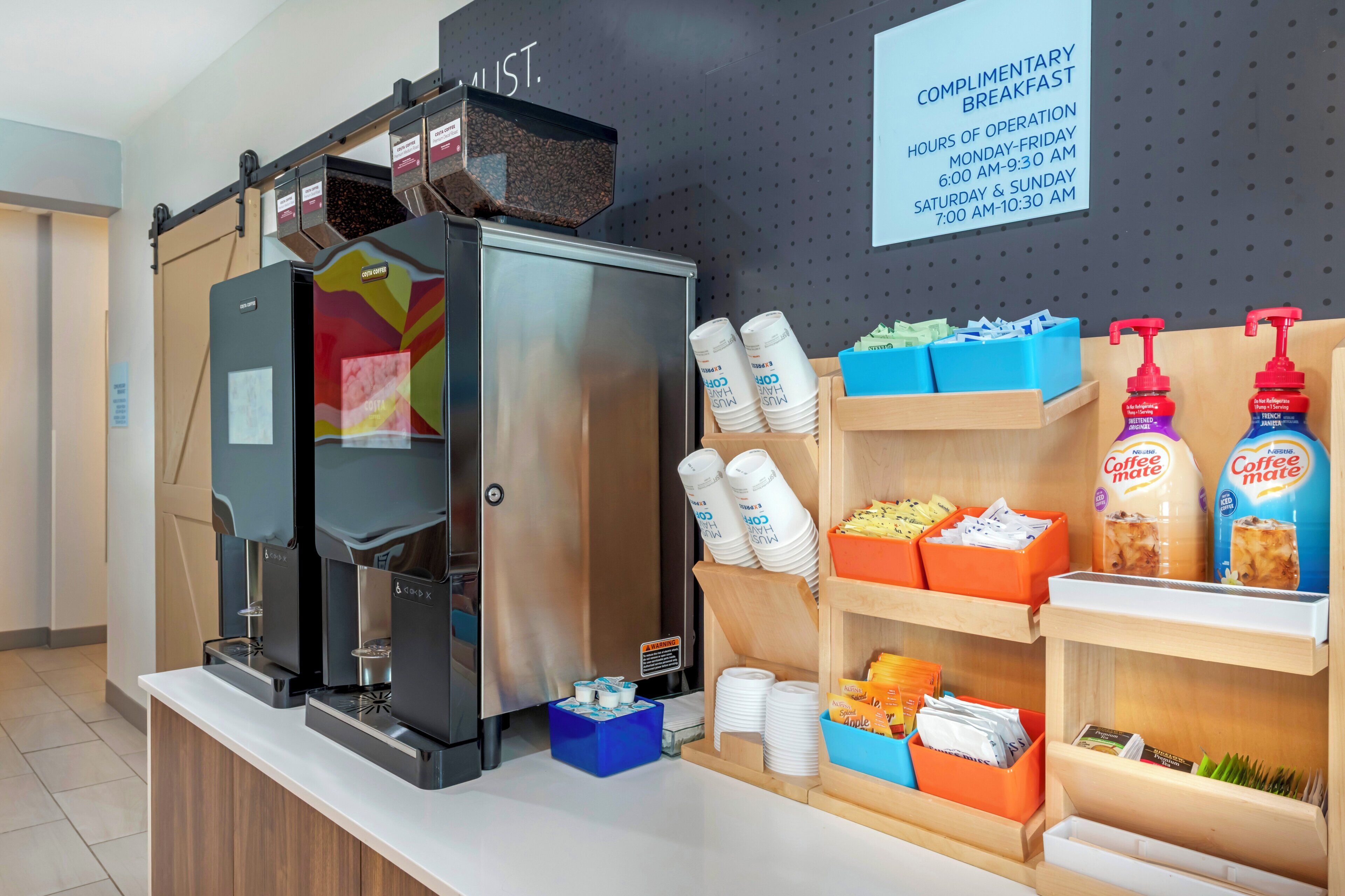 Ein Kaffeeangebot mit Kaffeemaschine, Einwegbechern und verschiedenen Kaffeesorten.