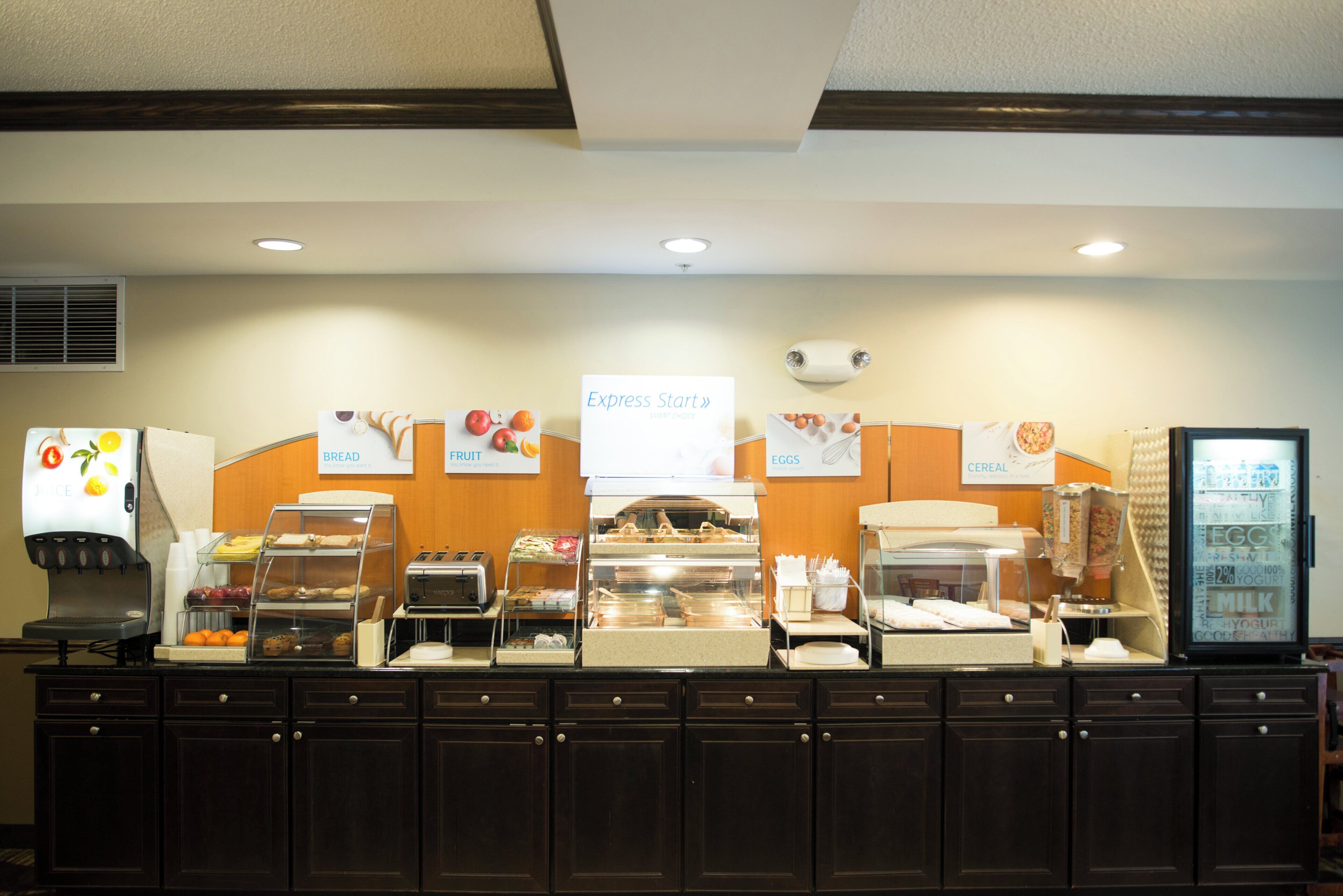 A buffet counter with labeled sections for bread, fruit, eggs, and cereal.