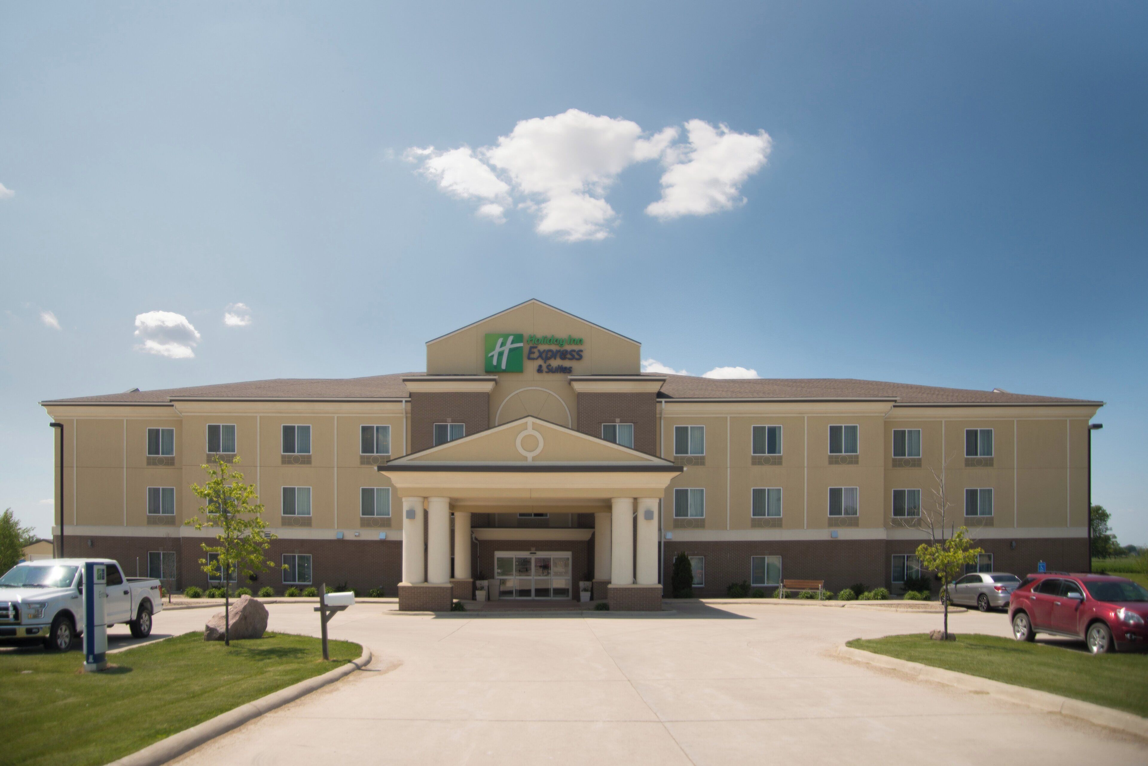 A Holiday Inn Express & Suites hotel with a central entrance, multiple windows, and a parking lot.