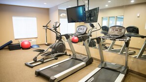 Un gimnasio con cintas de correr, bicicletas estáticas y pelotas de ejercicio.