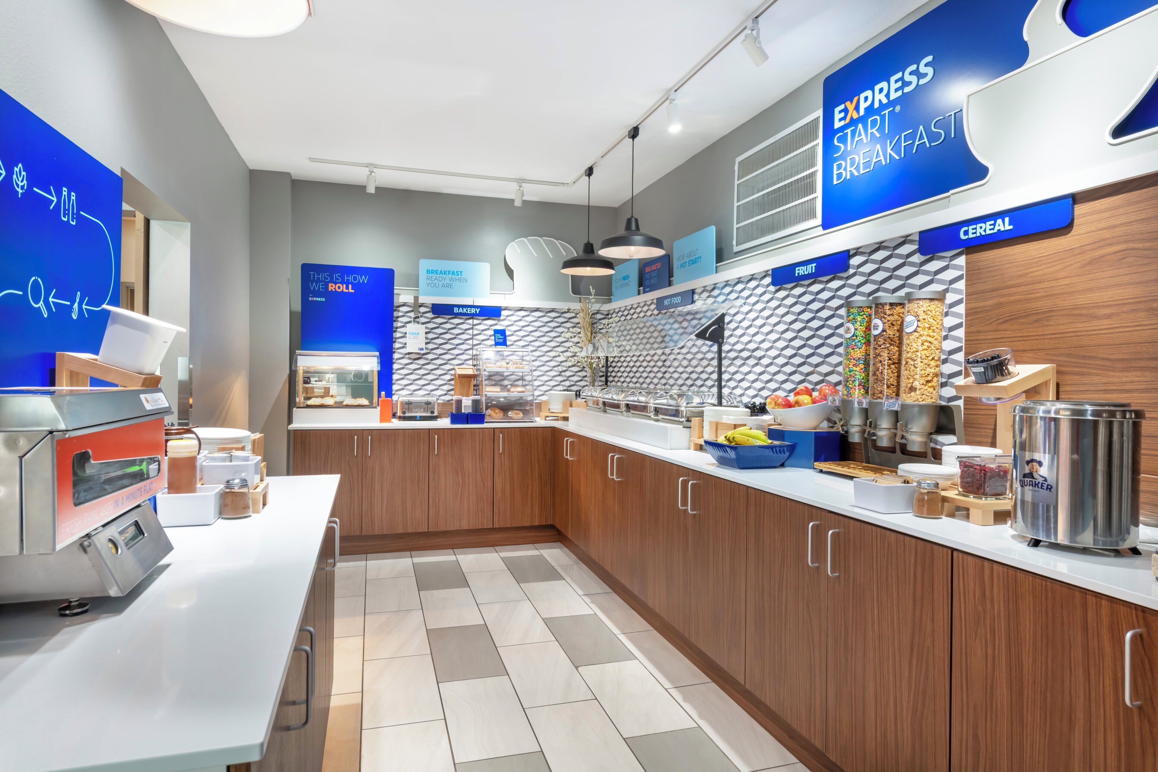 Un área de cocina moderna con barra desayunadora, una cafetera y varios dispensadores de alimentos.