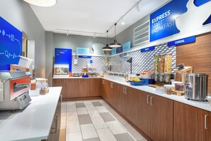 A modern kitchen area with a breakfast bar, a coffee machine, and various food dispensers.