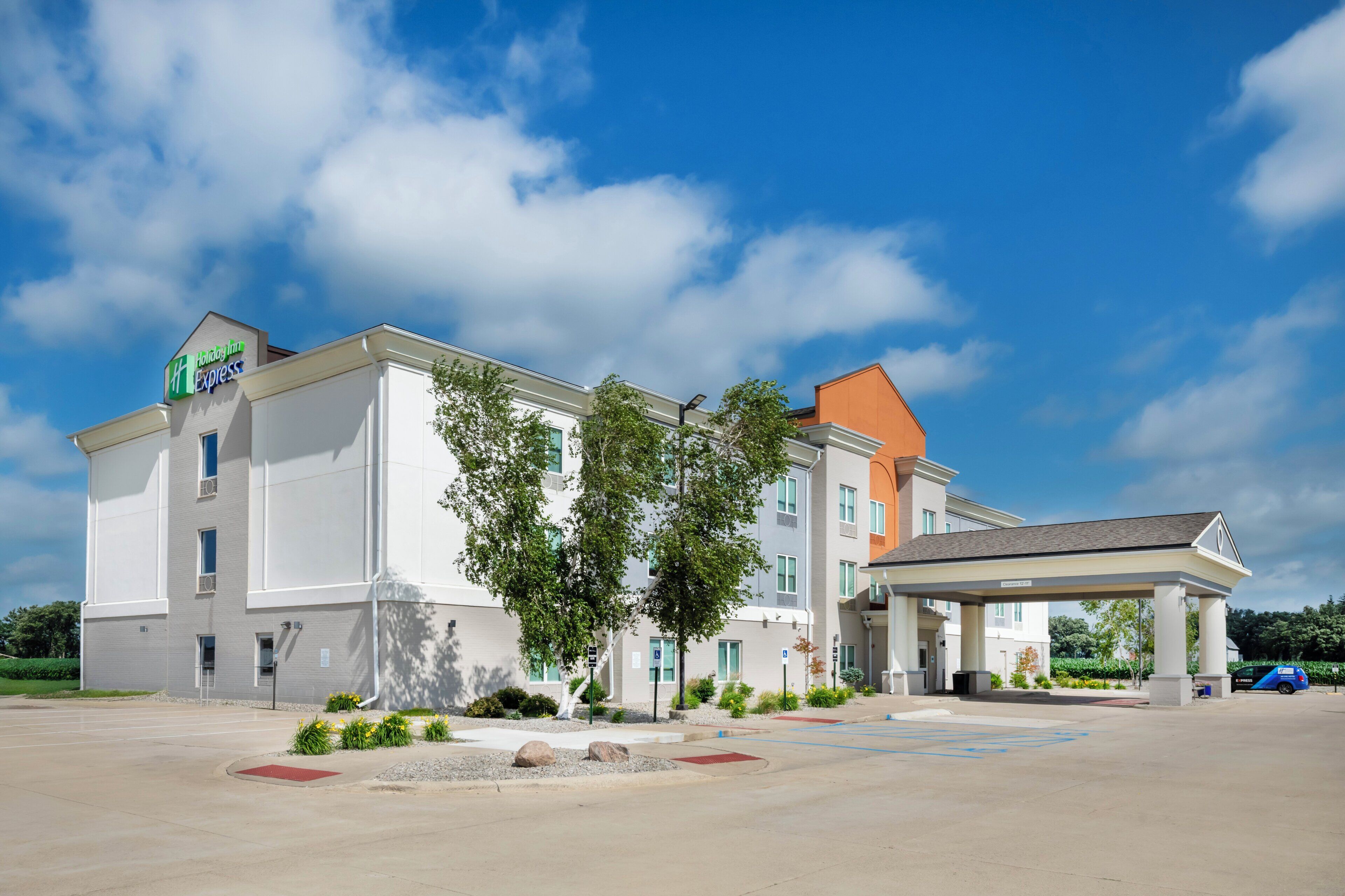 Un hotel Holiday Inn Express con una zona de estacionamiento techada y cielo despejado.