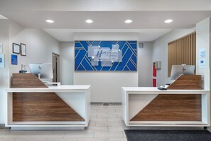 A reception area with two reception desks, a blue geometric wall design, and a check-in/out sign. - Holiday Inn Express Hotel & Suites Northwood by IHG (Northwood)