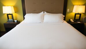 Una cama bien hecha con sábanas blancas, dos mesitas de noche con lámparas y un cabecero.