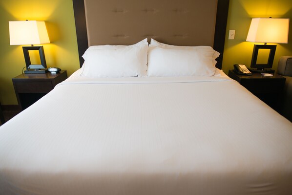 Una cama bien hecha con sábanas blancas, dos mesitas de noche con lámparas y un cabecero.