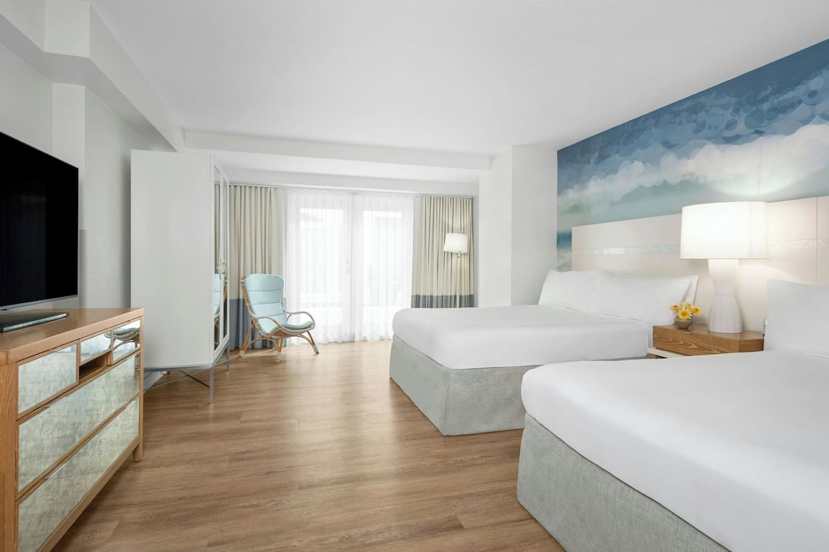 A hotel room with a large bed, a TV, a desk, and a chair.