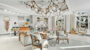 A modern hotel lobby with wicker furniture, a central seating area, and a unique ceiling design.