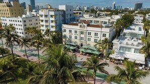 A hotel with a central courtyard, palm trees, and a view of the city skyline.
