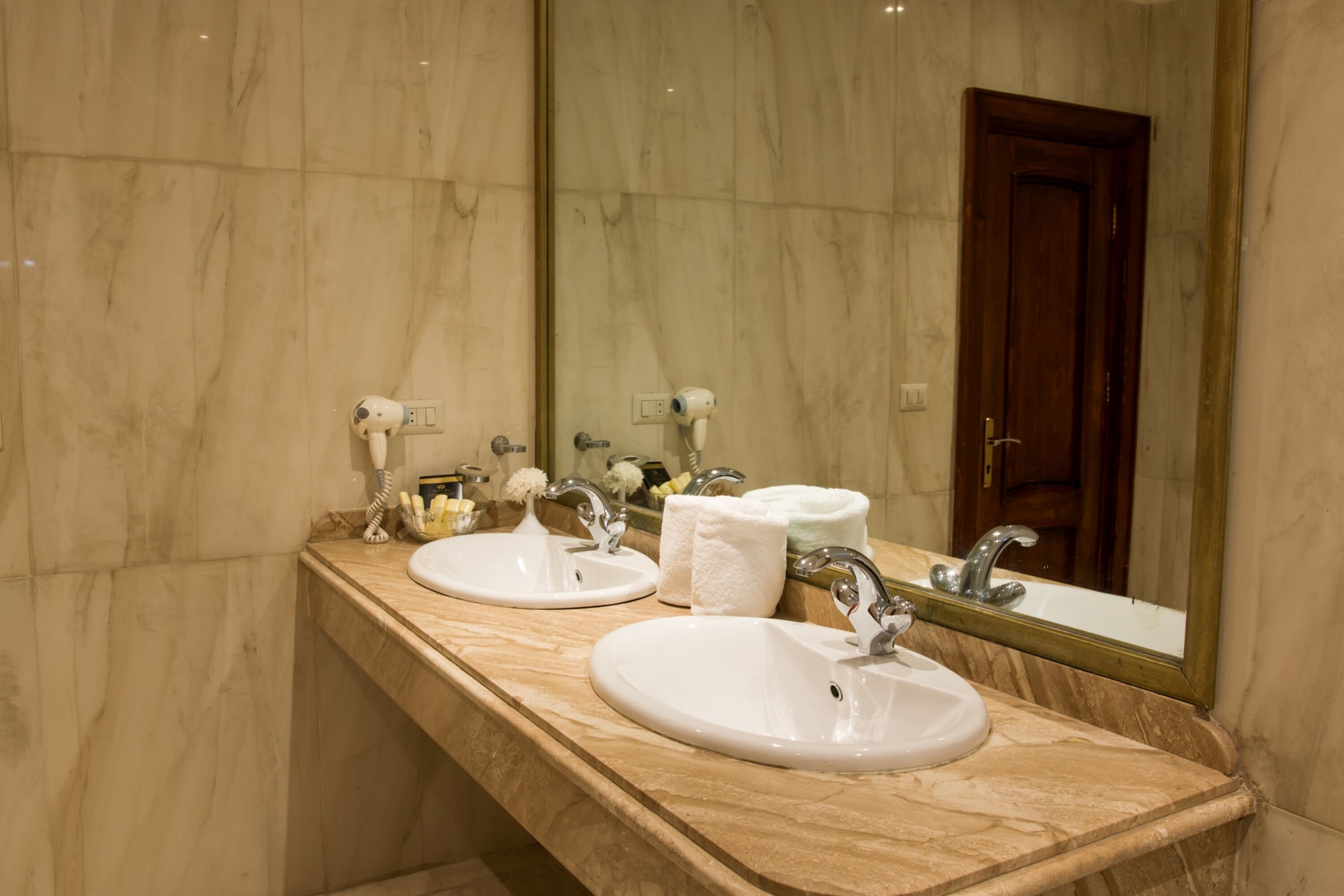 Une salle de bain avec deux lavabos, un miroir et une porte.