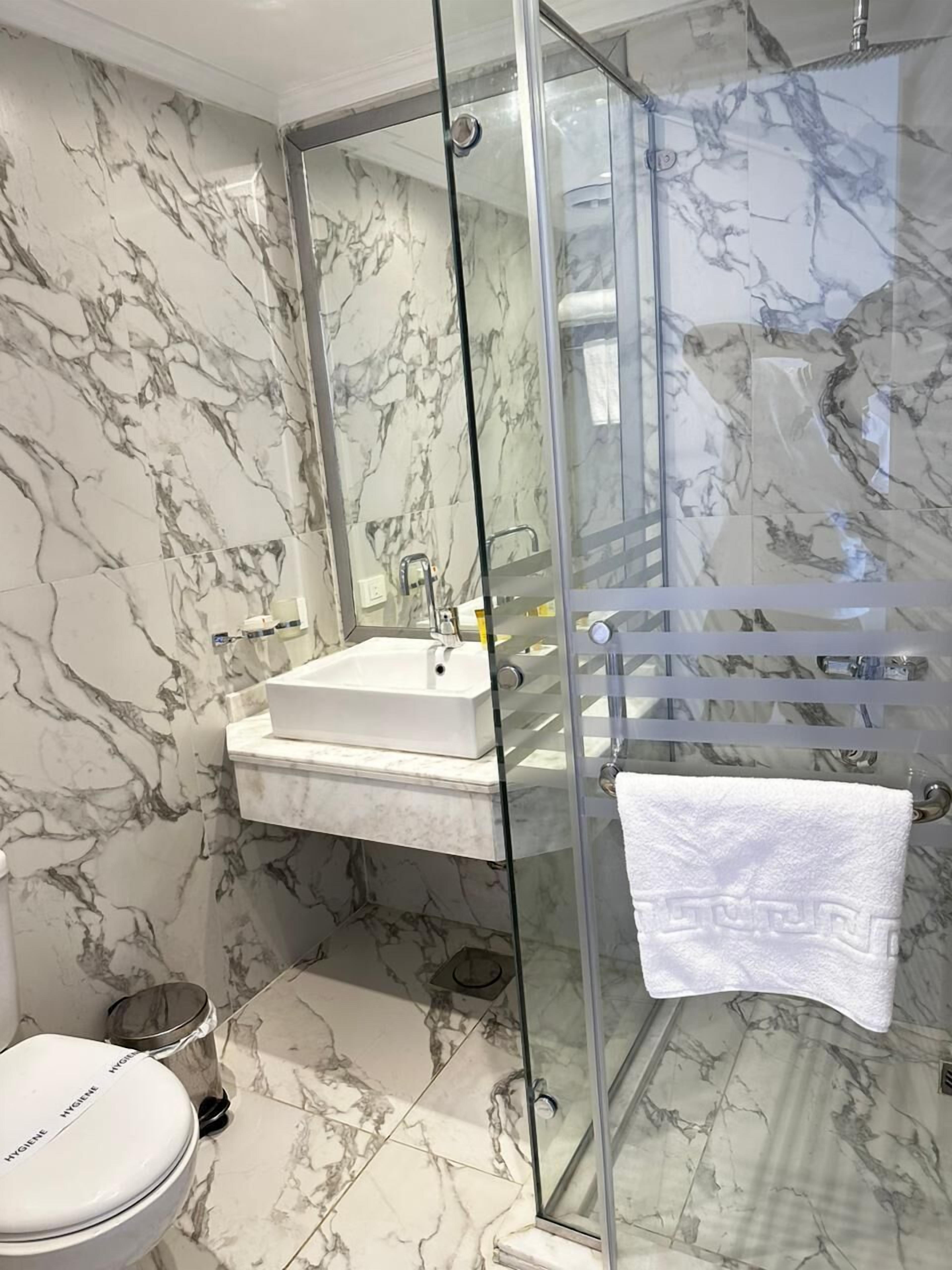 Un baño con ducha envuelta en cristal, un lavabo blanco y un inodoro.
