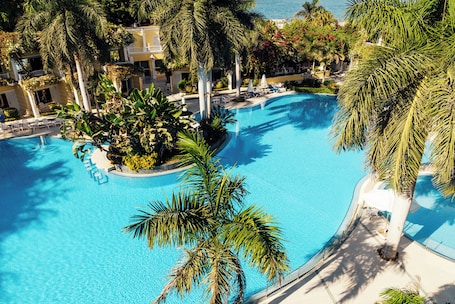 Una piscina techada, una piscina al aire libre, sombrillas