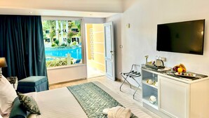 A hotel room with a bed, a TV, a small kitchenette, and a view of a pool. - Paradise Inn Beach Resort - Maamoura (Alexandria)