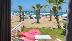 A balcony with a view of a beach, featuring white chairs, a red bean bag, and a table. - Paradise Inn Beach Resort - Maamoura (Alexandria)