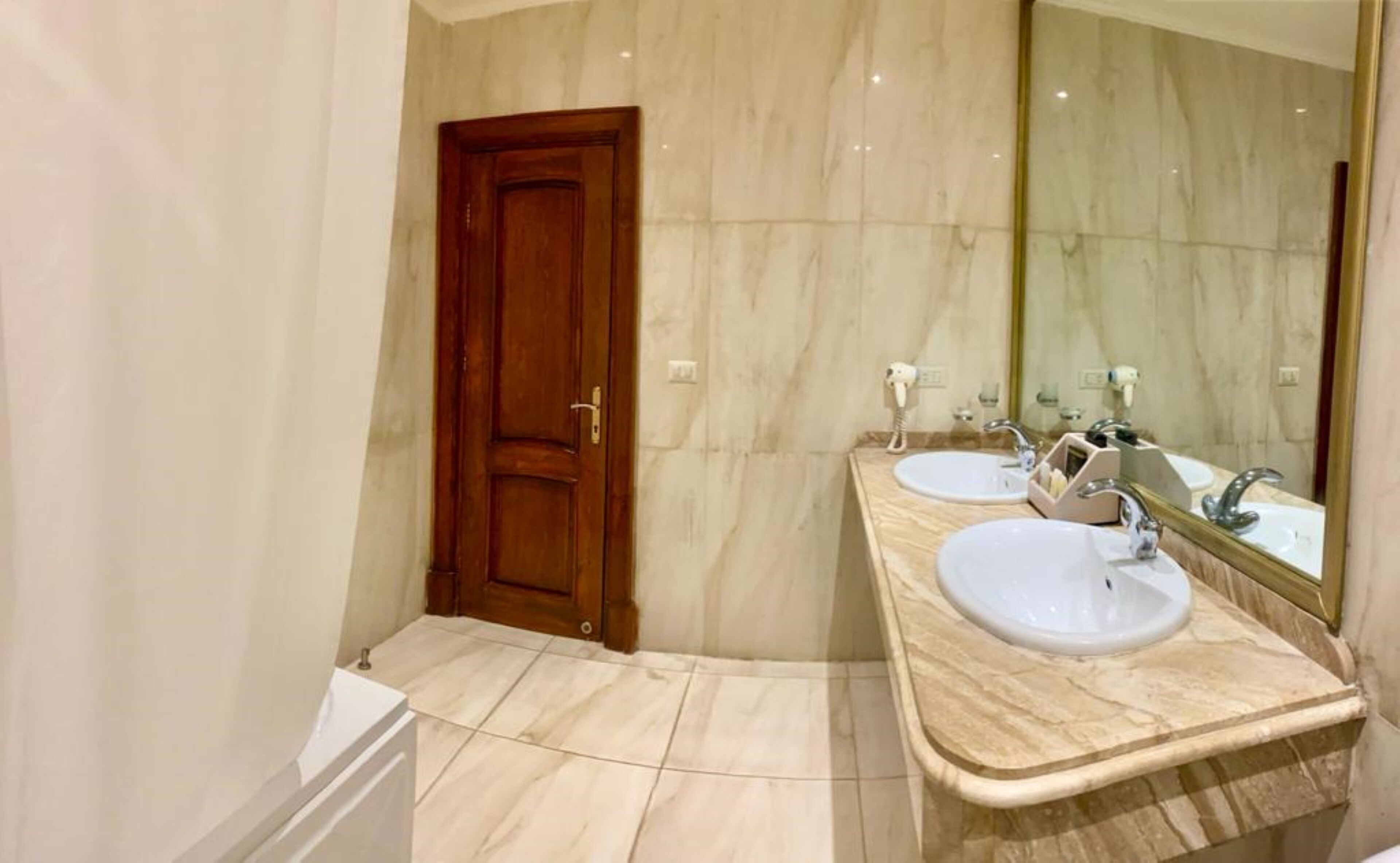 A bathroom with two sinks, a wooden door, and a large mirror.