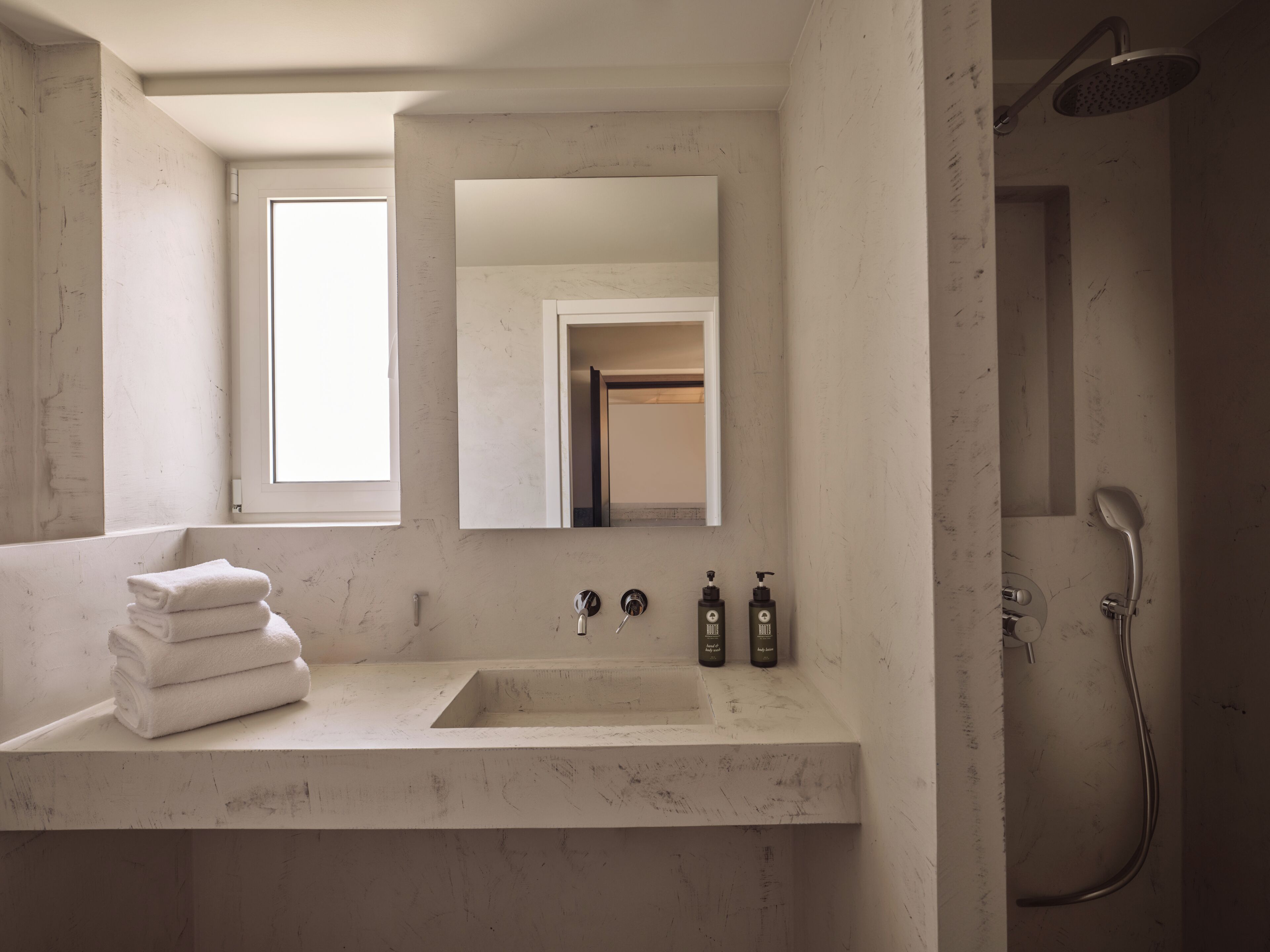 Un bagno con uno specchio grande, un lavabo con due rubinetti e una doccia.