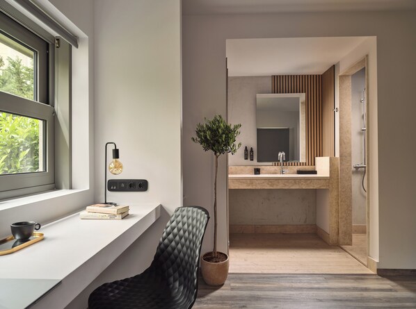 A modern bathroom with a large mirror, a sink, and a potted plant.