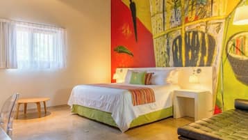 Un dormitorio con cama, mesitas de noche, una silla y un mural colorido en la pared.