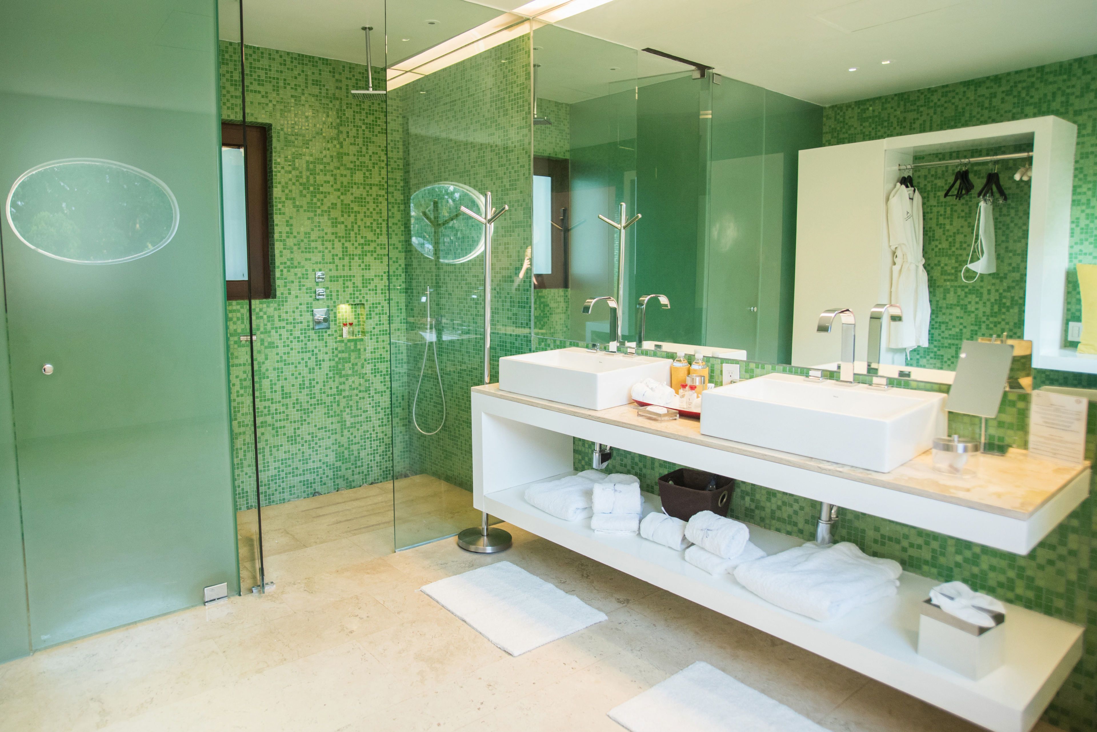 A modern bathroom with two sinks, a glass shower enclosure, and a large mirror.