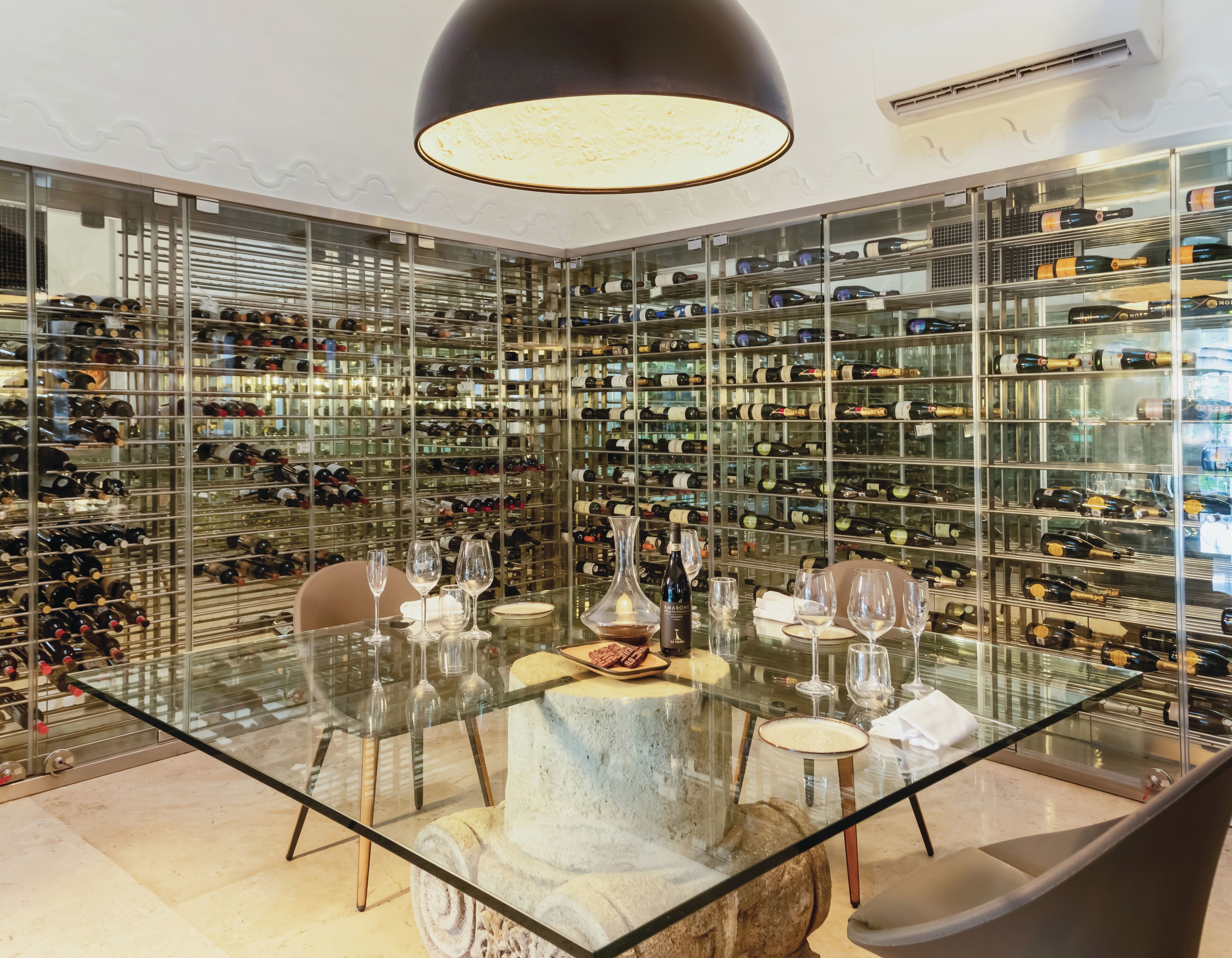 A wine cellar with glass shelves and a dining table.