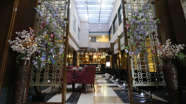 A hotel lobby with a high ceiling, skylight, and a checkered floor pattern. - Hotel City Park Airport (New Delhi)