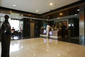 A modern hotel lobby with a reception desk, a large vase, and a marble floor. - Hotel City Park Airport (New Delhi)