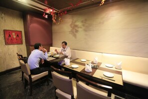 A conference room with a long table, chairs, and a sofa. There are plates, napkins, and a bottle on the table. - Hotel City Park Airport (New Delhi)