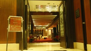 A hotel lobby with a red carpet, a chandelier, and a sign indicating a party hosted by Ajay Bansal at the Ball Room. - Hotel City Park Airport (New Delhi)