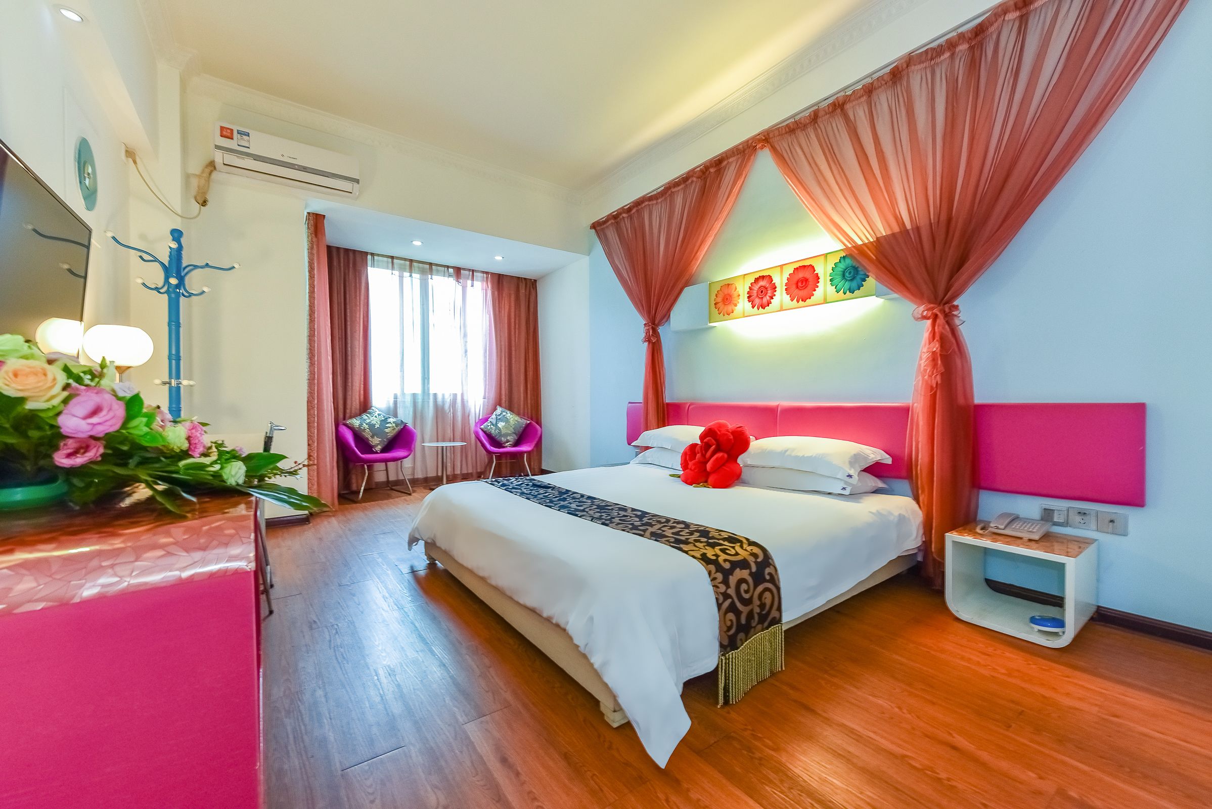 A hotel room with a large bed, a bedside table with a phone, a nightstand, and a decorative wall piece.