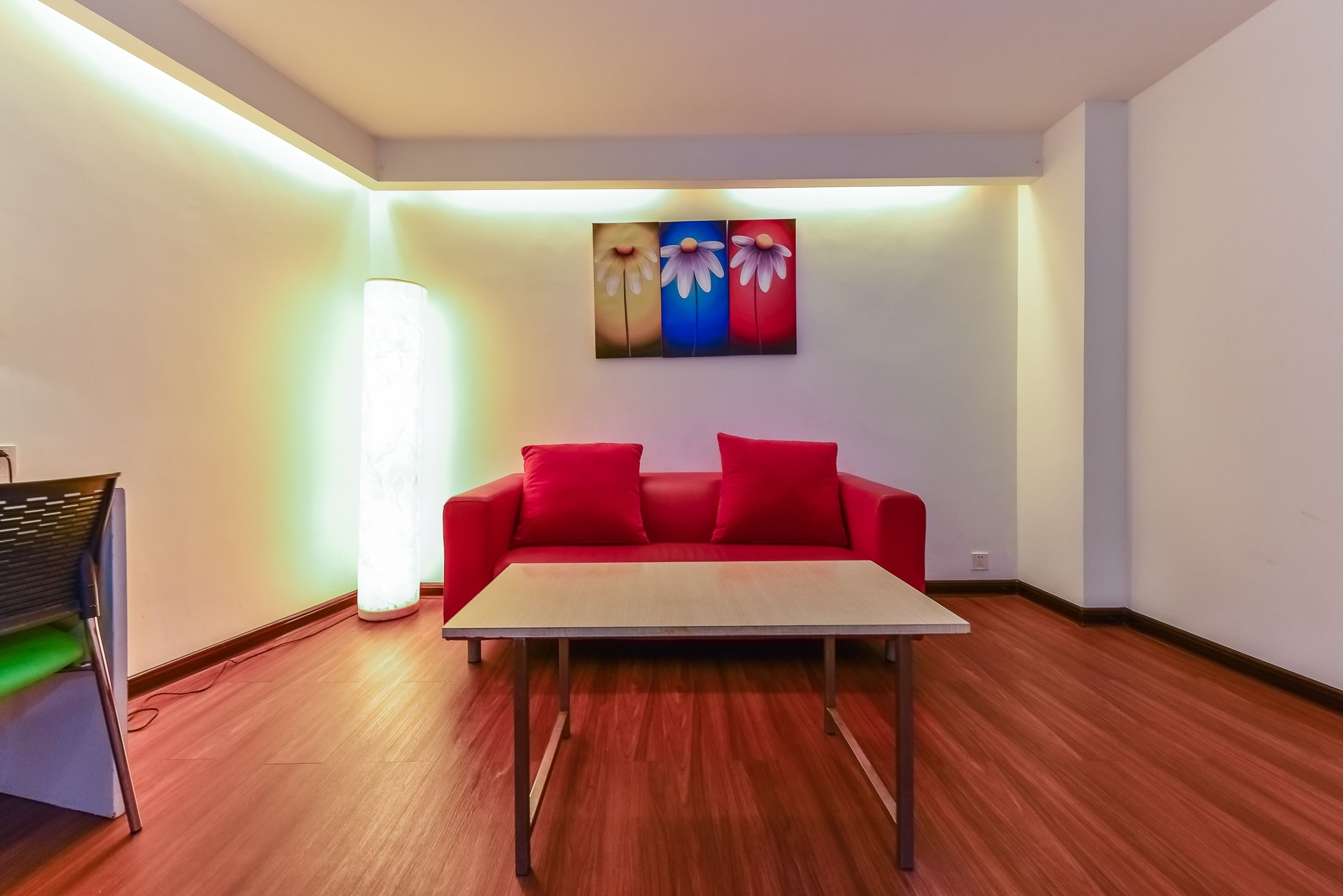 A modern room with a red sofa, a wooden table, and a painting on the wall.
