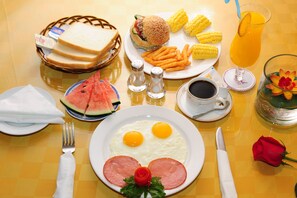 A breakfast table with eggs, ham, toast, a burger, corn, and a watermelon. - Grand 0773 Hotel (Guilin)