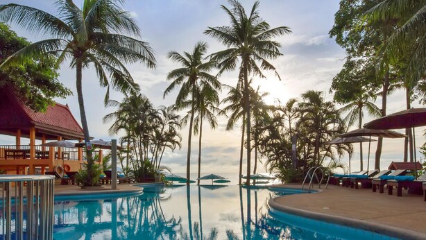 A pool area with palm trees, lounge chairs, and a building with a red roof. - Pinnacle Samui Resort SHA Plus (Koh Samui)