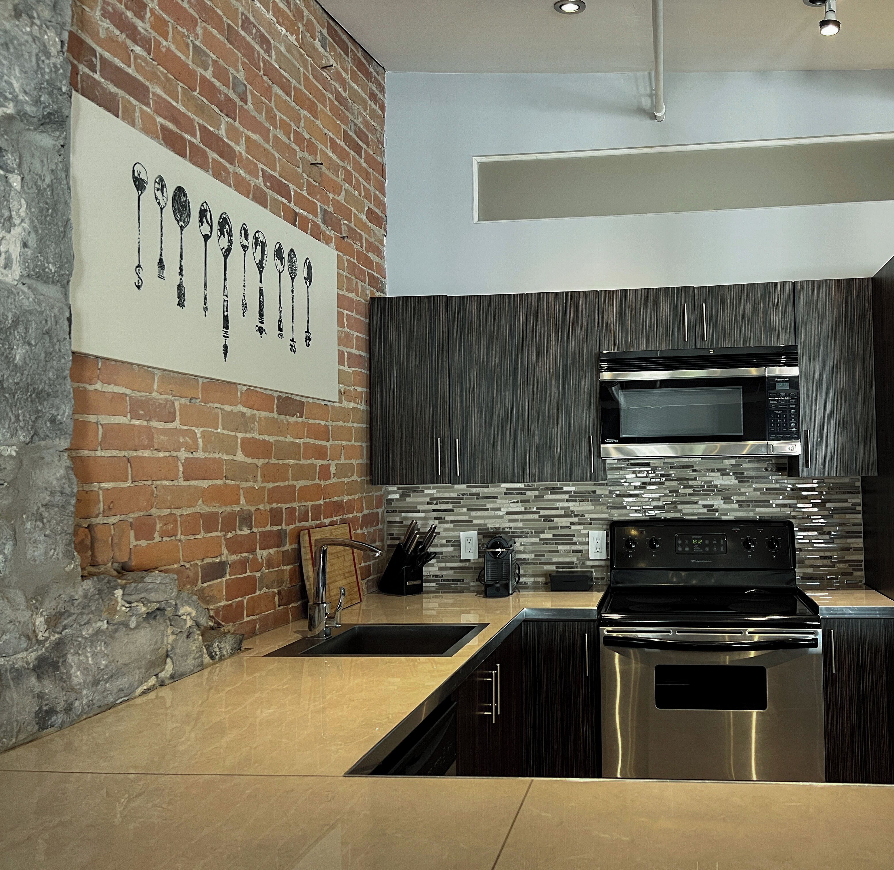 Una cocina moderna con pared de ladrillo, electrodomésticos de acero inoxidable y salpicadero de azulejos.