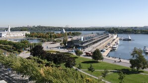 A waterfront hotel with a modern design, a marina with boats, and a park area with walking paths. - Lofts du Vieux-Port (Montreal)