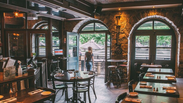 A restaurant interior with stone walls, arched windows, and wooden tables and chairs. - Lofts du Vieux-Port (Montreal)