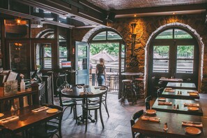 A restaurant interior with stone walls, arched windows, and wooden tables and chairs. - Lofts du Vieux-Port (Montreal)