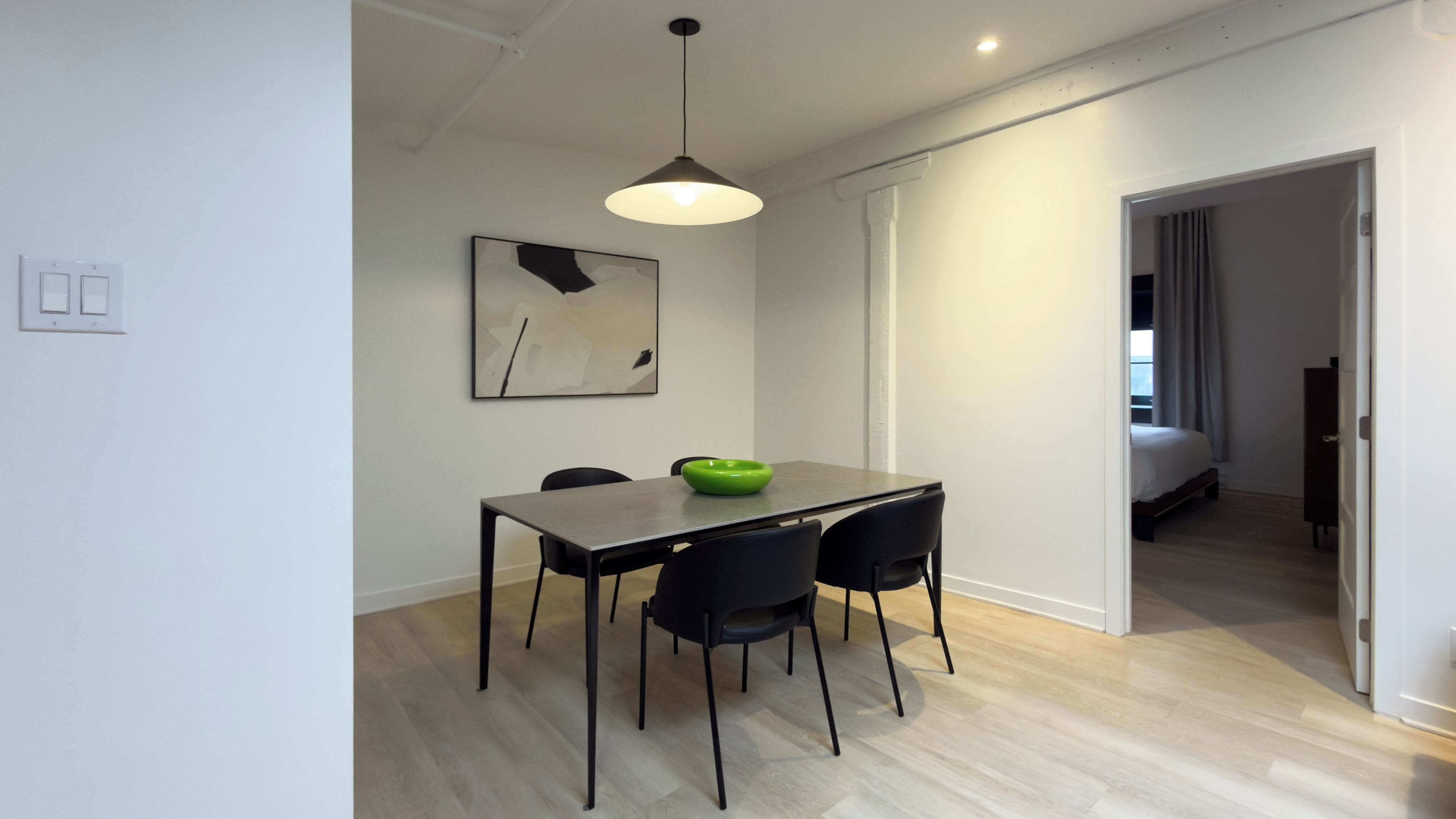 A modern dining area with a table, chairs, and a pendant light.