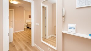 A hallway with a wooden floor, a mirror, a white shelf with a Wi-Fi sign, and a door leading to a bedroom. - Gestión de Alojamientos Rooms - Guest House (Pamplona)