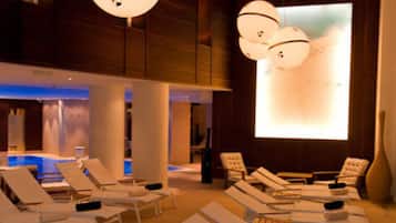 A spa area with lounge chairs, a hot tub, and a large screen displaying a beach scene.