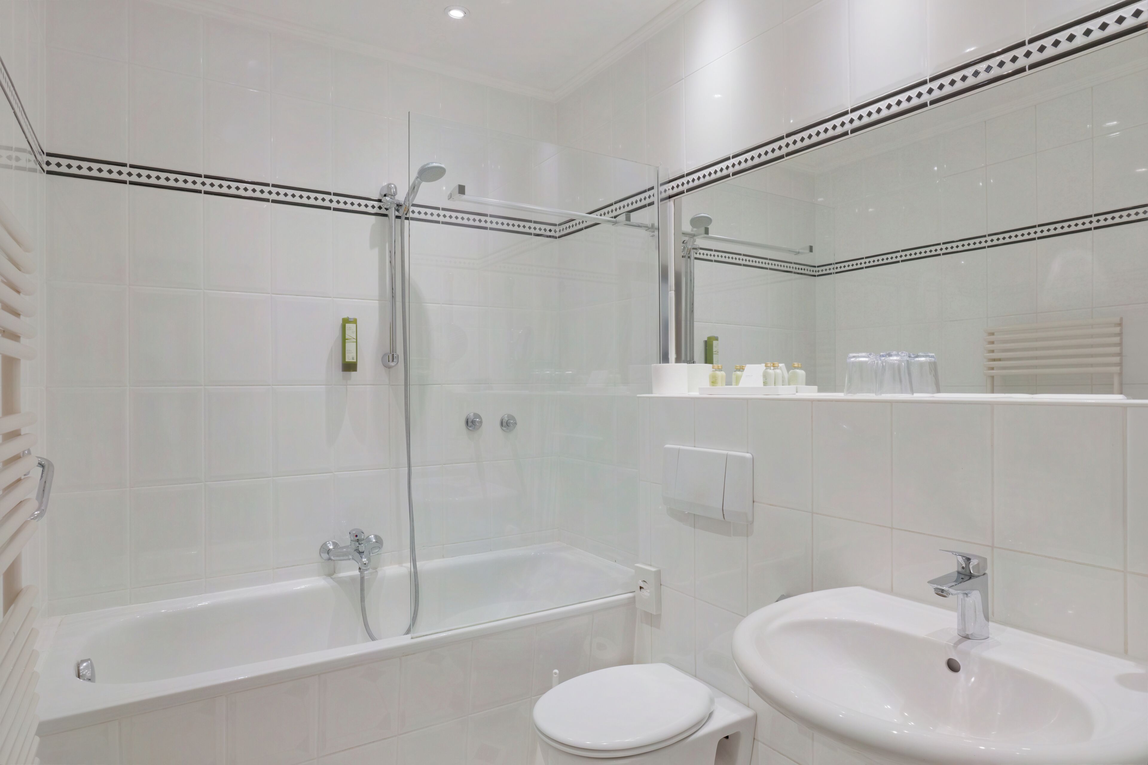 Een moderne badkamer met een douche met glazen wand, een vrijstaand bad en een wastafel op een voet.