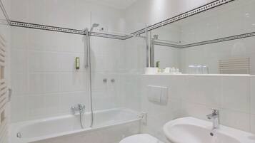 Een moderne badkamer met een douche met glazen wand, een vrijstaand bad en een wastafel op een voet.