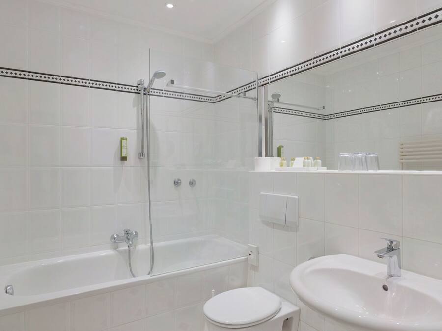 Een moderne badkamer met een douche met glazen wand, een vrijstaand bad en een wastafel op een voet.