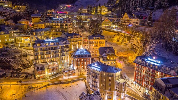 A snow-covered town with multiple buildings, including hotels and restaurants, illuminated at night. - Hotel Salzburger Hof (Bad Gastein)