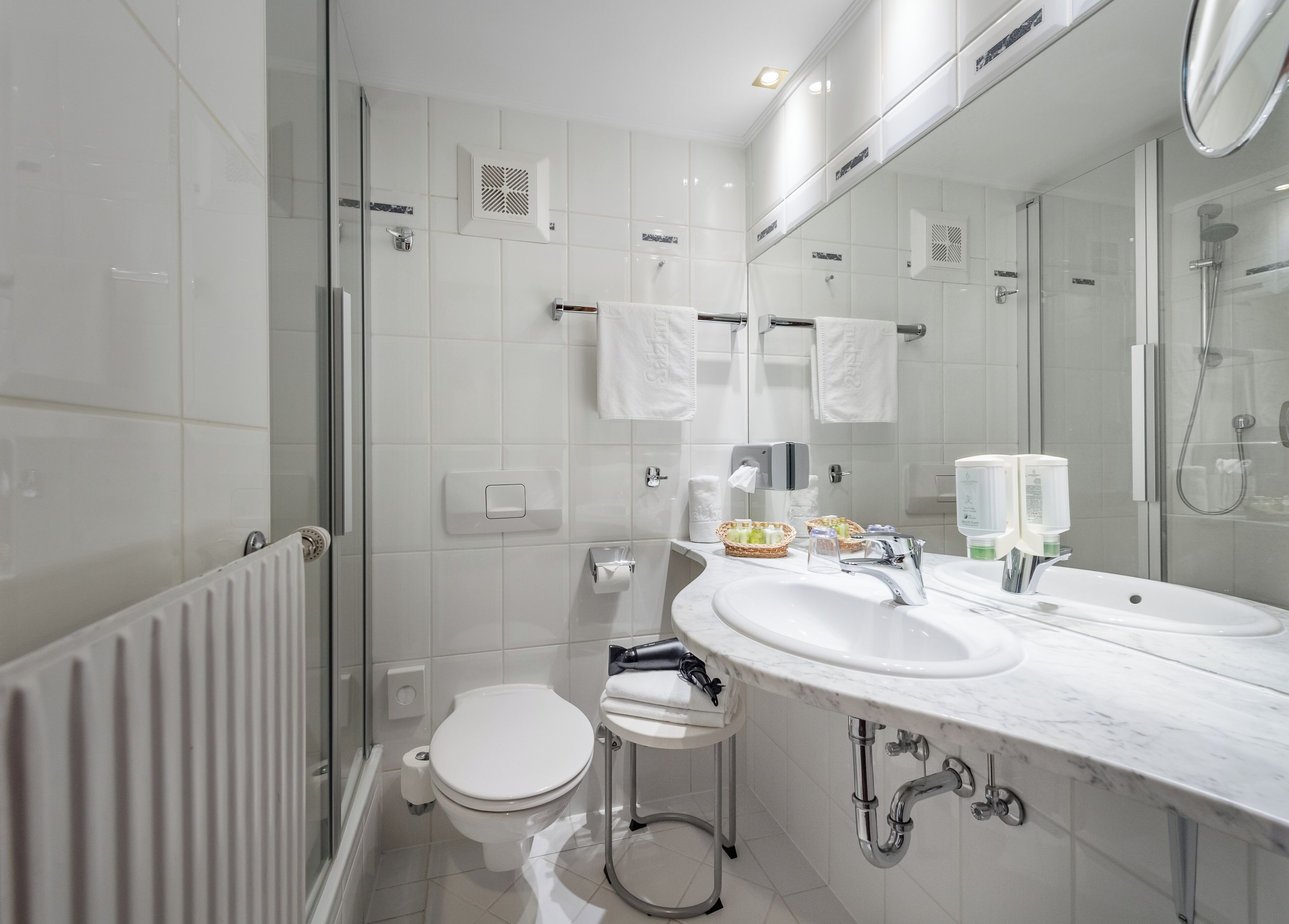 A modern bathroom with a toilet, bidet, and a large mirror above a sink.