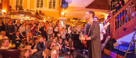 A man performing on stage in a room with a crowd watching.