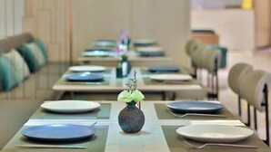 A dining area with tables set for service, each with a vase of flowers and plates. - Orange Hotel Shanghai Longbai New Village Subway Station (Shanghai)